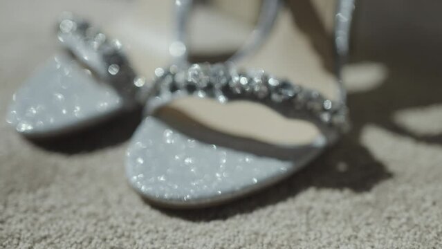 Shiny women's wedding accessories. Action. Delicate shoes with bright sequins, a purse and wedding rings neatly lying next to each other.