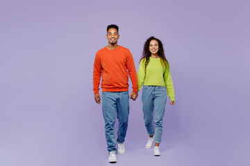 Obraz premium Full body front view young couple two friends family man woman of African American ethnicity wear casual clothes hold hands walk go strolling together isolated on pastel plain light purple background.
