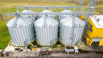 silver silos on agro manufacturing plant for processing drying cleaning and storage of agricultural products, flour, cereals and grain. Flying a drone over iron barrels of grain. quadcopter photo