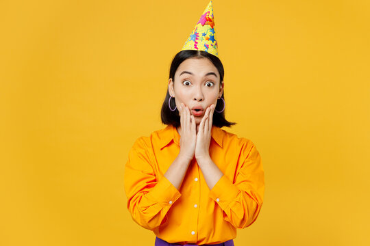 Happy Fun Impressed Surprised Stunned Astonished Amazed Young Woman Wears Casual Clothes Hat Celebrating Look Camera Hold Face Isolated On Plain Yellow Background. Birthday 8 14 Holiday Party Concept.