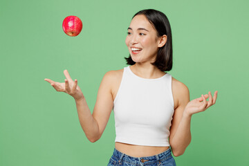 Young fun vegetarian woman wear white clothe hold in hand toss up ripe red apple playing isolated...