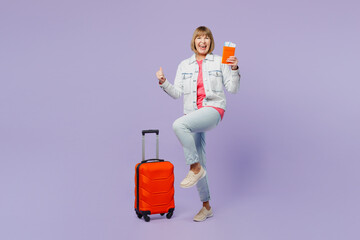 Traveler fun elderly woman 50s years old wear casual clothes hold bag passport ticket isolated on plain purple background Tourist travel abroad in free spare time rest getaway Air flight trip concept.