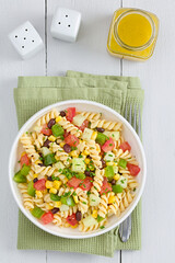 Fresh homemade colorful vegan fusilli pasta salad with beans, corn, tomato, cucumber and green bell...