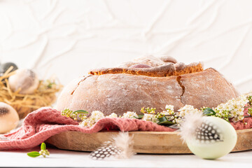 Portuguese traditional Easter cake with eggs. Typical Folar de Vale de Ilhavo, Aveiro, Portugal. Blossom flowers and colorful painted eggs decorated with feathers on easter table.