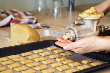 Pressing dough through a grinder to prepare homemade Christmas cookies