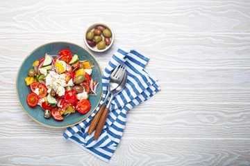 Gordijnen Greek fresh healthy colorful salad with feta cheese, vegetables, olives in blue bowl on rustic white wooden background top view, Mediterranean diet, traditional cuisine of Greece. Space for text © somegirl