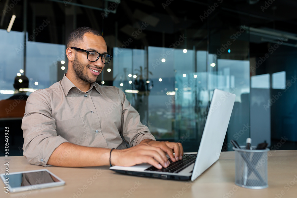 Wall mural young successful indian programmer working inside modern development company, man using laptop to wr