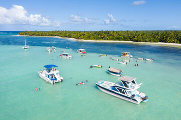 Speed boats with people having fun in caribbean sea near tropical island with palm trees. Dominican Republic. Aerial view - obrazy, fototapety, plakaty