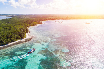 Speed boats with people having fun in caribbean sea near tropical island with palm trees. Dominican Republic. Aerial view