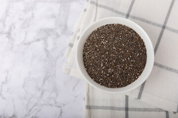A bowl of chia seeds on a texture table. Superfood. Proper nutrition. Diet. Healthy food. Place for text. Place to copy.