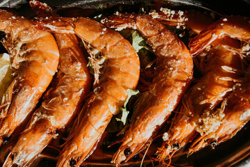 Fresh shrimps not peeled, on an aluminum plate with salt and lemon in a restaurant as a dish.