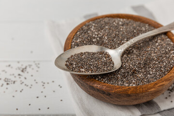 Bowl and spoon with chia seeds on a white wooden table. Superfood. Proper nutrition. Diet. Healthy food. Place for text. Place to copy.