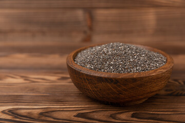 Chia seeds in a bowl on a brown textural background. Superfood. Proper nutrition. Diet. Healthy food. Place for text. Place to copy.