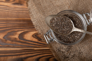 Chia seeds in a bowl and spoons on a brown textural background. Superfood. Proper nutrition. Diet. Healthy food. Place for text. Place to copy.
