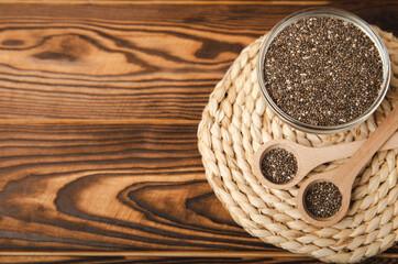 Fototapeta na wymiar Chia seeds in a bowl and spoons on a brown textural background. Superfood. Proper nutrition. Diet. Healthy food. Place for text. Place to copy.