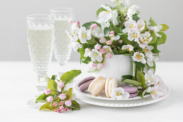 Beautiful composition with delicious French macarons and spring flowers in a white cup. Sweet dessert, early spring white and pink flowers, wedding decor, bride morning