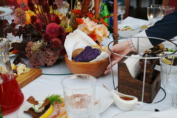 table setting for a festive dinner. waiter places a plate of bread on the table.