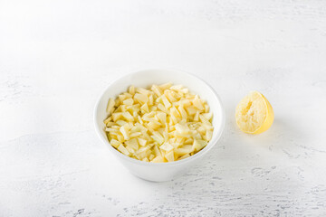 White ceramic bowl with sliced apples with lemon juice on a light gray background. Cooking homemade apple pie