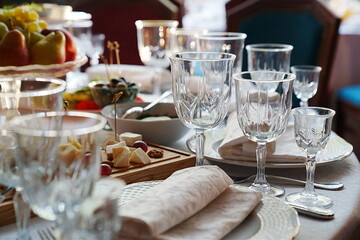 table setting for a festive dinner. empty wine glasses, tableware and snacks.