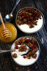 Two breakfast bowls with crunches, honey, berries and yogurt.