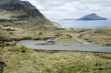 Car driving on the curved road to Norðradalur, a small village in Faroe Islands, Northern Europe