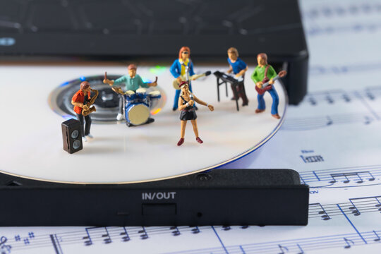 a white cd in a cd player, on which a band of music is playing a concert