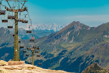 Beautiful alpine summer view with reflections in a lake and a chairlift at the famous Weisssee...