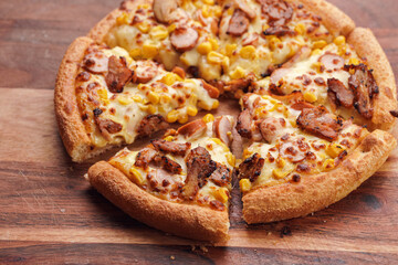 Freshly baked american pan pizza with a lot of cheese, chicken sausage, thin and crispy kebab meat and corn on a wooden board, take-away dish - Powered by Adobe