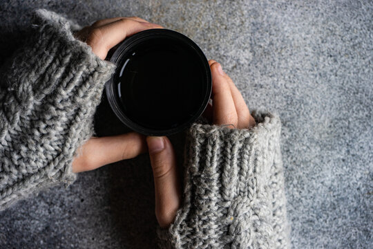 Overhead view of a person wearing fingerless gloves holding a warm drink