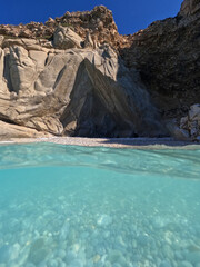Underwater split photo of famous paradise turquoise pebble beach of Seychelles in island of Ikaria, Aegean sea, Greece