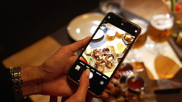 Girl takes a picture of a delicious dish that was served to her in a restaurant on her mobile phone