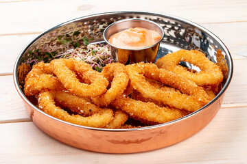 Onion rings fried in breading with cheese sauce