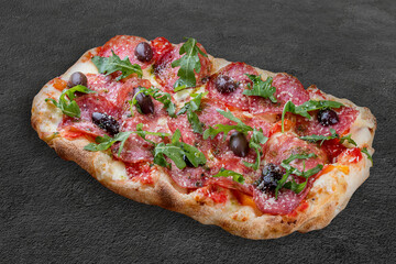 Pizza Diavolo with chorizo, rucola, jalapeno, chili, kalamata, pesto. Roman pizza rectangular on dark background