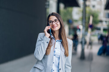 Business woman standing outside the office building and using smartphone