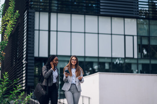 Two Multiracial Business Woman Meeting Outside And Using A Smartphone