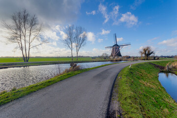 Countryside landscape view of traditional Dutch windmill under blue sky in winter, Polder and water...