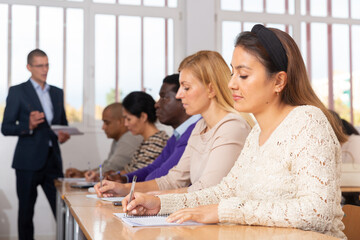 Portrait of attentive focused hispanic woman on lesson in school auditorium. Adult learning and education concept..