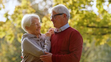 Smiling senior couple standing close together outdoor in nature. High quality photo