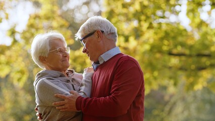 Two loving grey-haired people together outdoor in autumn nature. High quality photo