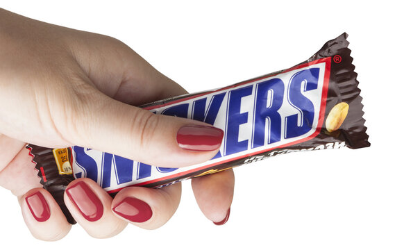 female hand holding a Snickers chocolate bar. Isolated on a transparent background