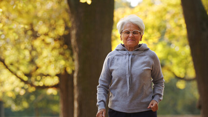 Older grey-haired woman jogging in the park . High quality photo