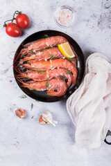 Langoustines in a pan with garlic and cherry tomatoes on a marble background. View from above 