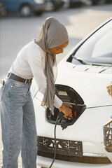 African American girl charging electro car at the electric gas station