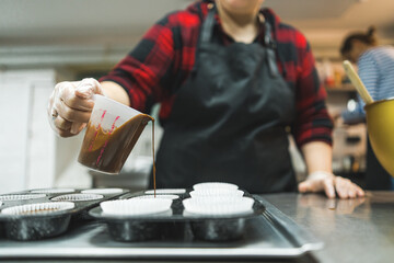 Muffin recipe. Paper moulds prepared by a cook. Unrecognizable pastry chef pouring chocolate cupcake batter into moulds. High quality photo