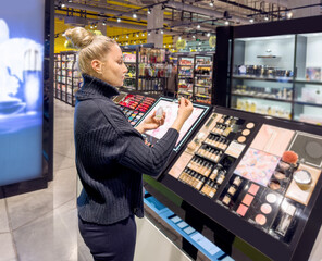 Woman buying make up at cosmetics section in store. choosing cosmetics, perfumes, creams and shampoos, Using tester.