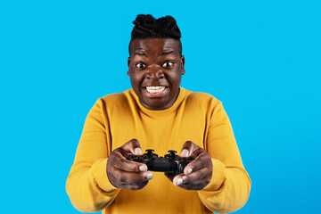 Excited black guy playing video games with joystick over blue background
