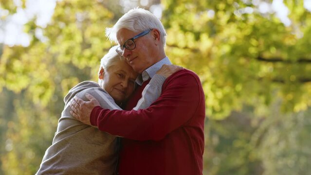 Two loving grey-haired people hugging outdoor in autumn nature. High quality photo