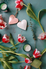Red tulips, hearts and candles on a wooden table. Valentines, mothers, womens day, wedding or birthday flat lay concept. Top view.