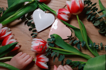 Bouquet of tulips on the table with hearts. Valentines, mothers, women's day, wedding or birthday flat lay concept. Top view.