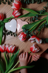 Fototapeta na wymiar Bouquet of tulips on the table with hearts. Valentines, mothers, women's day, wedding or birthday flat lay concept. Top view.
